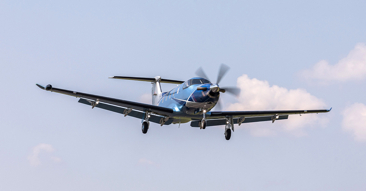 Photo of small blue aircraft flying on sunny day