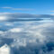 Expansive aerial landscape with dramatic lenticular cloud above distant mountains and valleys displaying cloud layers at varying altitudes and temperatures