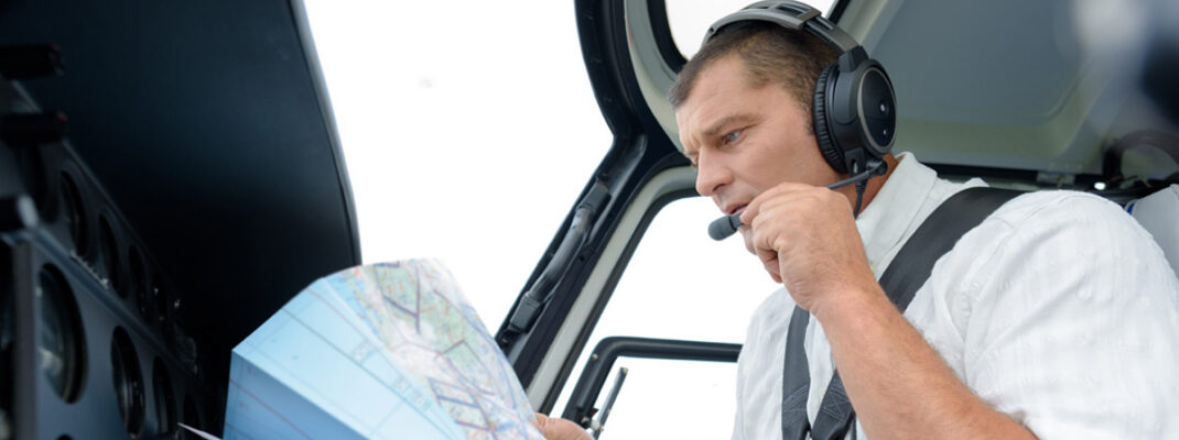 pilot talking into headset while holding aeronautical chart