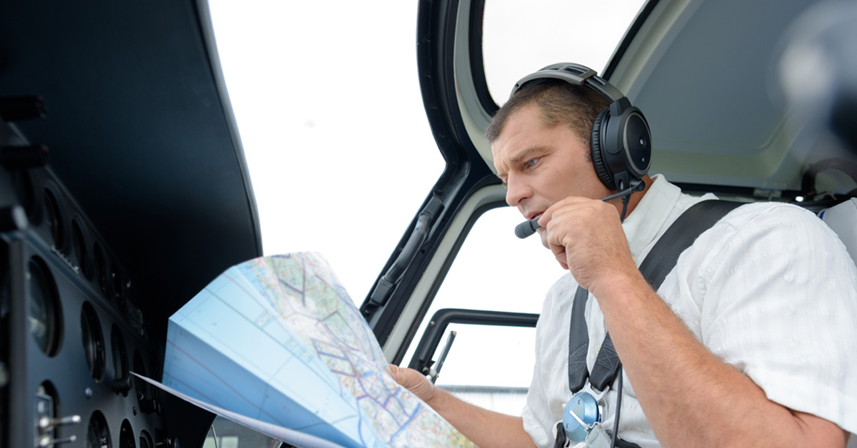 pilot talking into headset while holding aeronautical chart