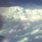 Photo taken from small engine airplane with nose and blades visible in flight with storm in distance.