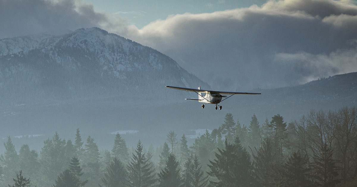 Scenic Light Aircraft Landing Over Misty Forest and Mountain Landscape. Cessna 172 single engine aircraft