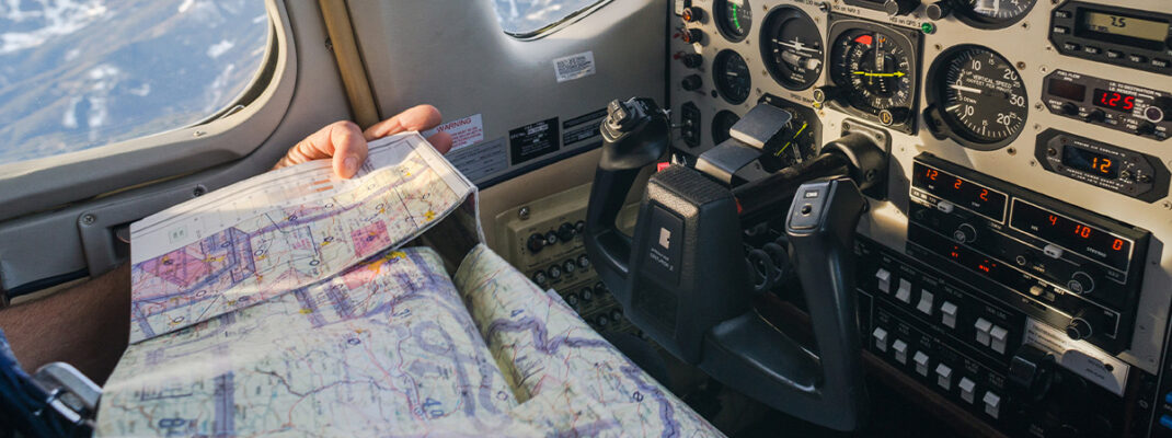 Pilot navigating while reading sectional chart in cockpit