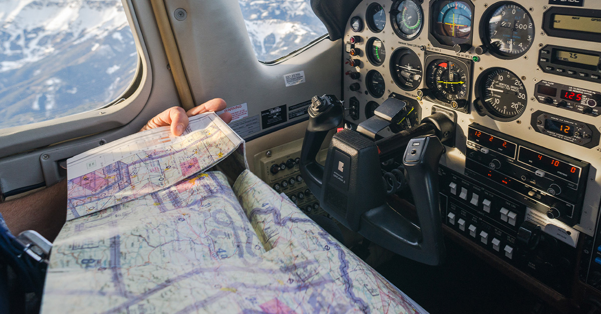 Pilot navigating while reading sectional chart in cockpit