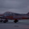 Piper Archer aircraft on taxiway at dusk with aircraft and runway lights visible