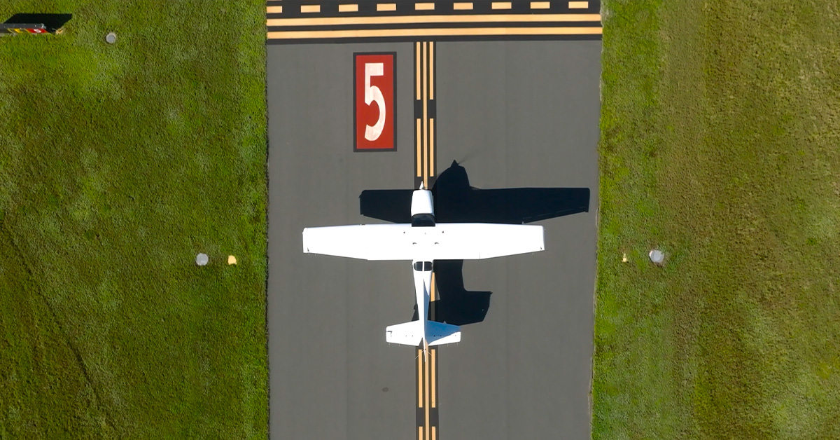 Aerial views of white aircraft on taxiway at small airfield