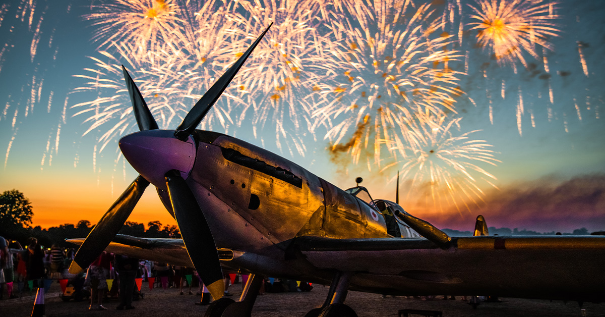 Fireworks light up the sky behind a grounded Spitfire
