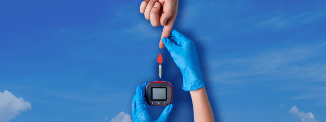 two hands completing a diabetes blood test atop sky background