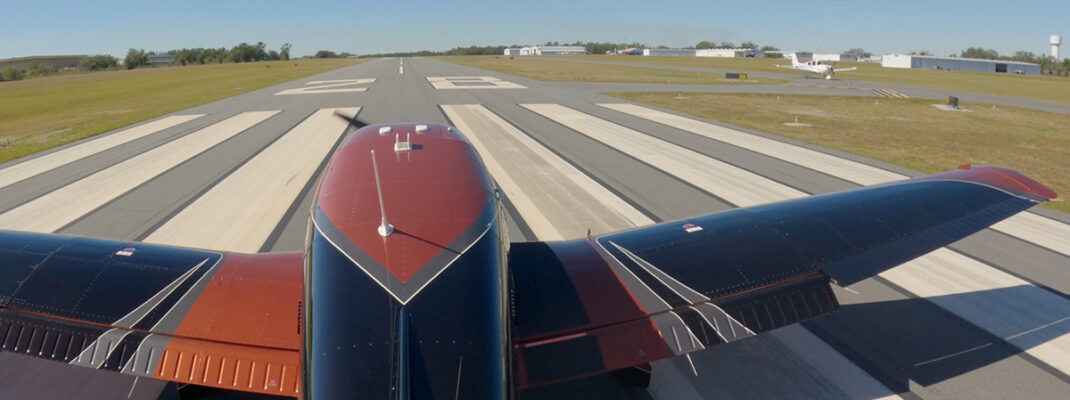 Piper Archer upon takeoff in crosswind with airfield and other aircraft visible on taxiway