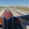 Piper Archer upon takeoff in crosswind with airfield and other aircraft visible on taxiway