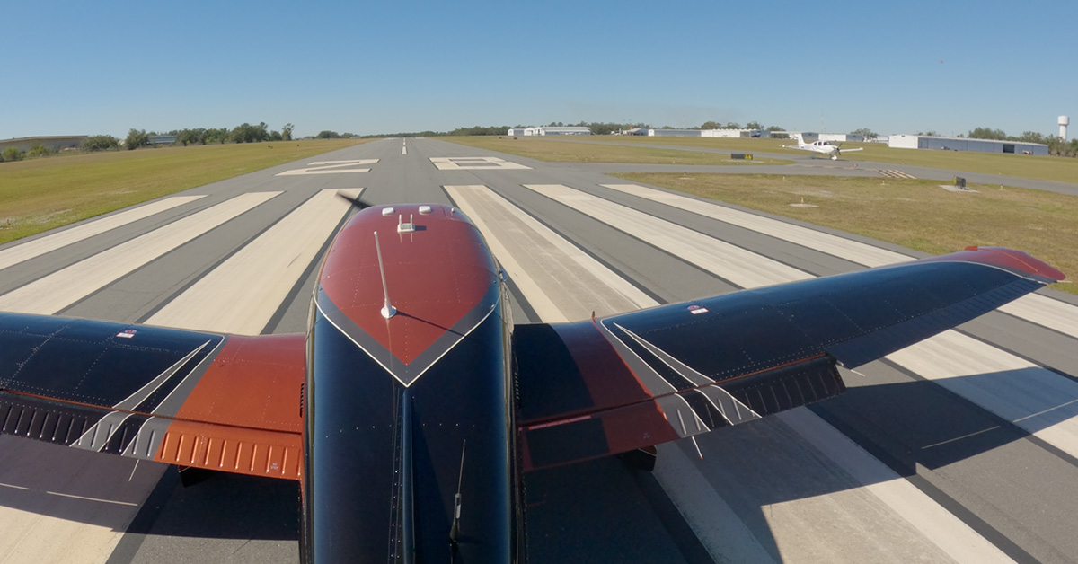 Piper Archer upon takeoff in crosswind with airfield and other aircraft visible on taxiway