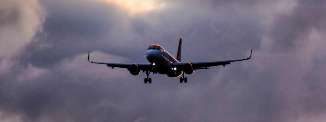 commercial airplane flying through dark menacing storm clouds