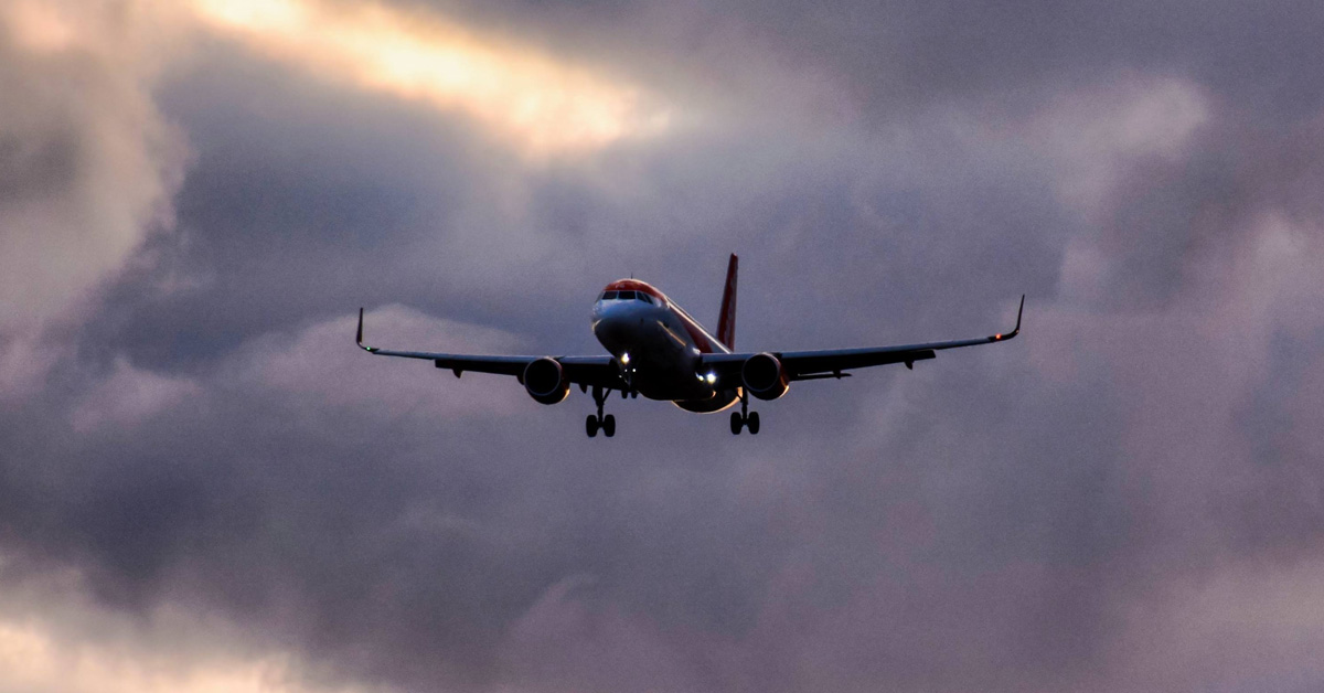commercial airplane flying through dark menacing storm clouds