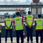 Five CAU student pilots in yellow vests on runway