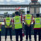 Five CAU student pilots in yellow vests on runway