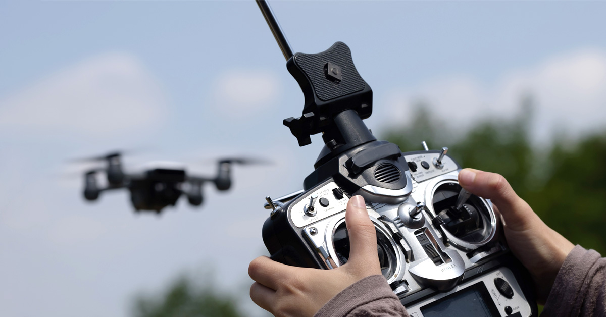 Point of view drone pilot holing remote with drone in the sky.