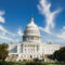 US capitol building from a distance with clouds in the background.