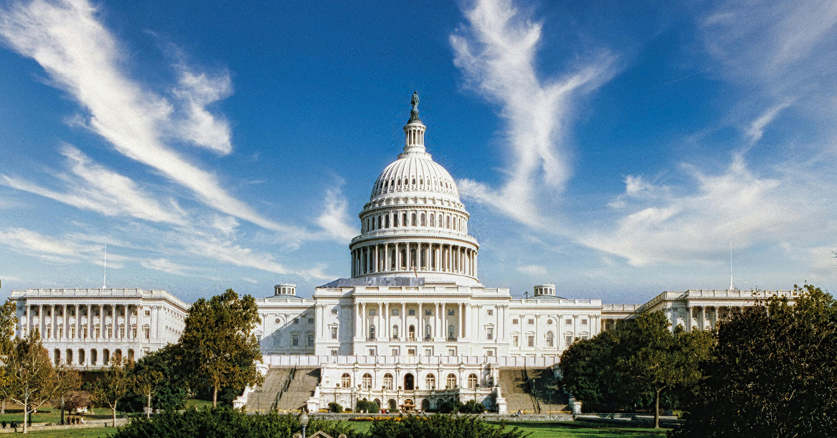 US capitol building from a distance with clouds in the background.