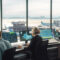 four air traffic controllers at computers in tower looking over runway.