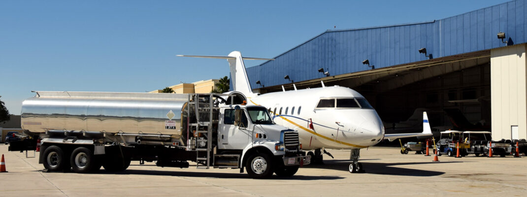 airport view of private jet being refueled via truck in from of a hangar.