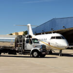 airport view of private jet being refueled via truck in from of a hangar.
