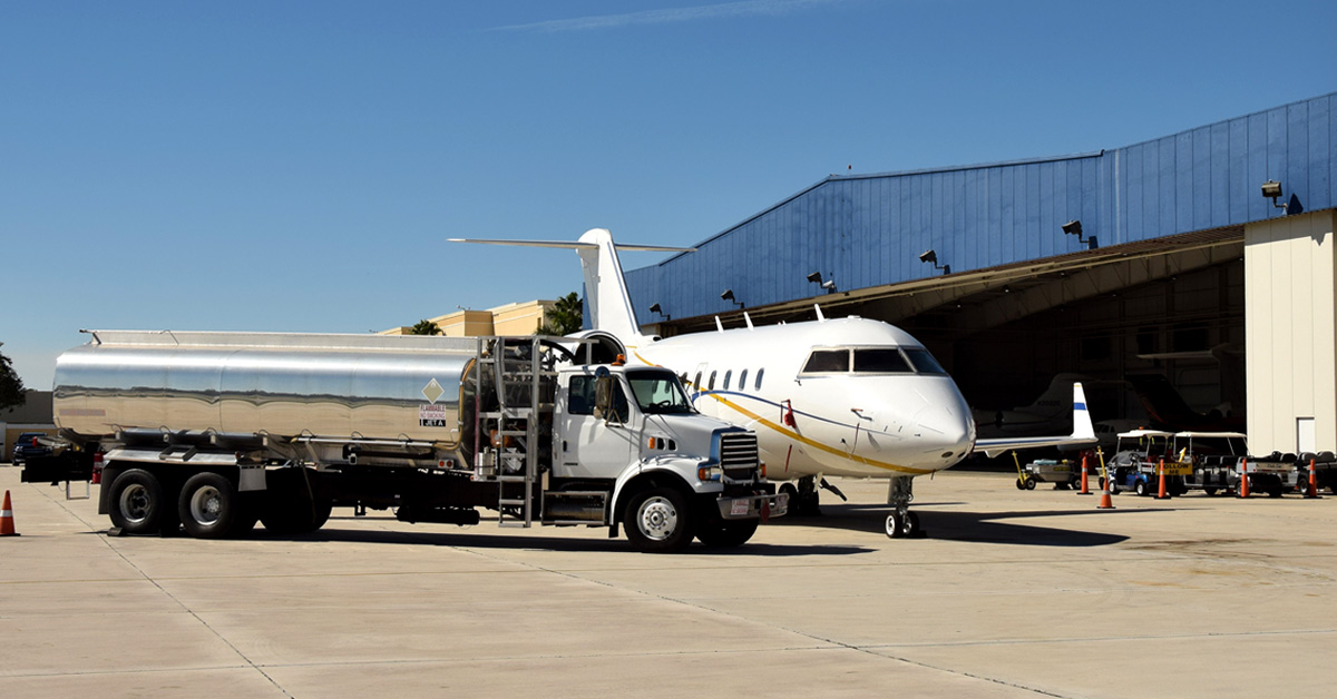 airport view of private jet being refueled via truck in from of a hangar.