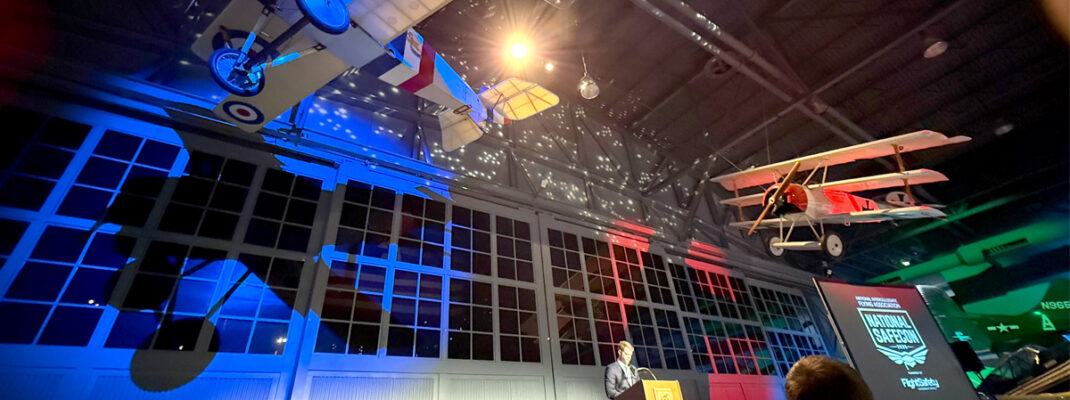 2025 NIFA SAFECON award ceremony with airplanes on ceiling and colored lights in background.