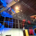 2025 NIFA SAFECON award ceremony with airplanes on ceiling and colored lights in background.