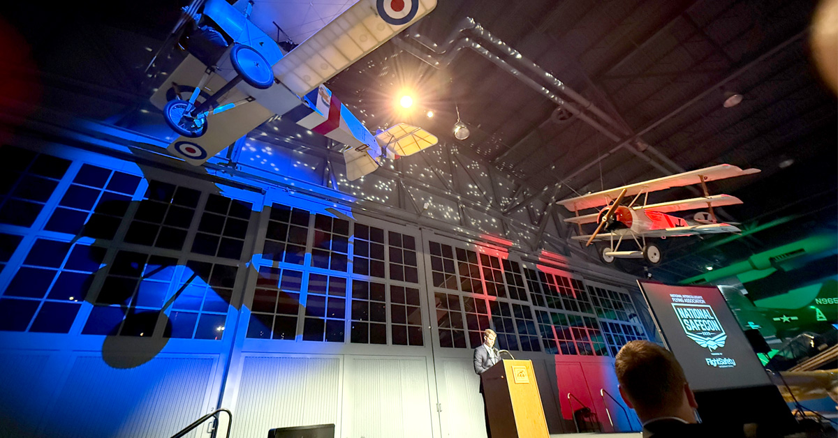2025 NIFA SAFECON award ceremony with airplanes on ceiling and colored lights in background.