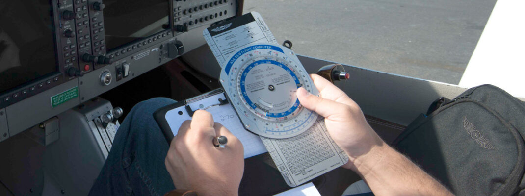 pilot in plan using ASA E6-B Flight Computer with instruments in background.