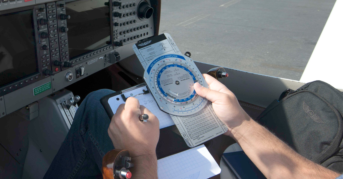 pilot in plan using ASA E6-B Flight Computer with instruments in background.